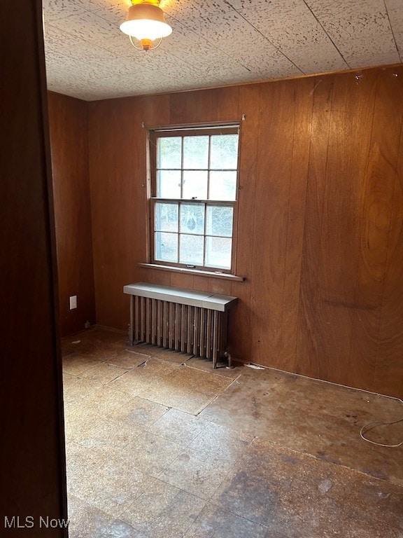 empty room with wood walls and radiator