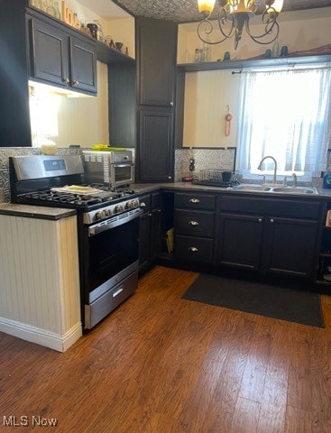 kitchen featuring stainless steel appliances, sink, dark hardwood / wood-style floors, a notable chandelier, and decorative backsplash