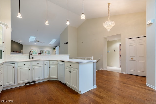 kitchen with white dishwasher, sink, hardwood / wood-style floors, white cabinets, and a skylight