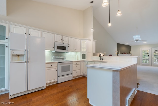 kitchen featuring kitchen peninsula, white appliances, hardwood / wood-style floors, decorative light fixtures, and high vaulted ceiling