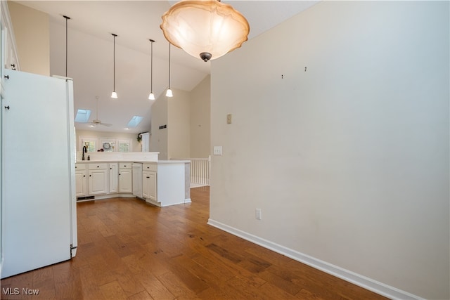 kitchen featuring kitchen peninsula, light wood-type flooring, white cabinets, white fridge, and a skylight