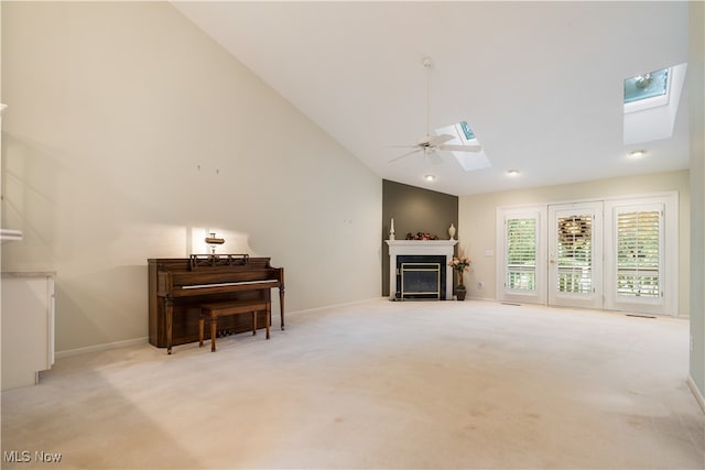 carpeted living room with high vaulted ceiling, a skylight, and ceiling fan