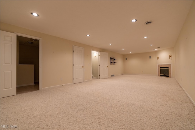 unfurnished living room featuring a tiled fireplace and light colored carpet