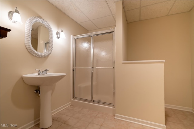 bathroom with a paneled ceiling, a shower with shower door, tile patterned floors, and sink