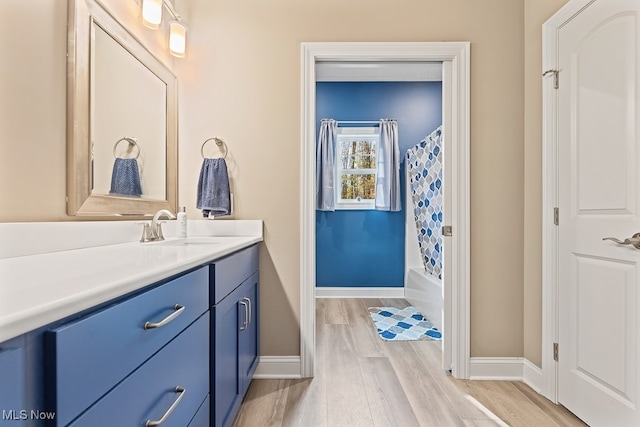 bathroom with hardwood / wood-style floors, vanity, and shower / bathtub combination with curtain