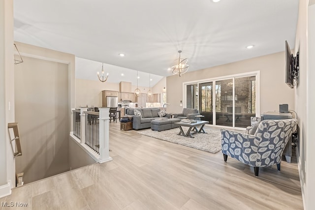 living room with light hardwood / wood-style flooring, an inviting chandelier, and lofted ceiling