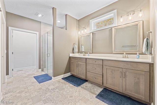 bathroom with tile patterned flooring, vanity, an enclosed shower, and a textured ceiling