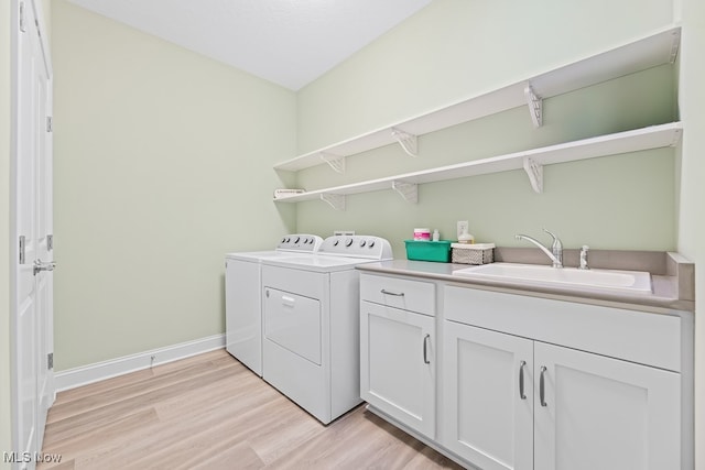 laundry area featuring cabinets, light hardwood / wood-style floors, washing machine and dryer, and sink