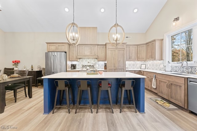 kitchen with an inviting chandelier, light hardwood / wood-style flooring, appliances with stainless steel finishes, a kitchen island, and a breakfast bar area