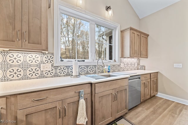 kitchen with sink, tasteful backsplash, light hardwood / wood-style flooring, stainless steel dishwasher, and vaulted ceiling