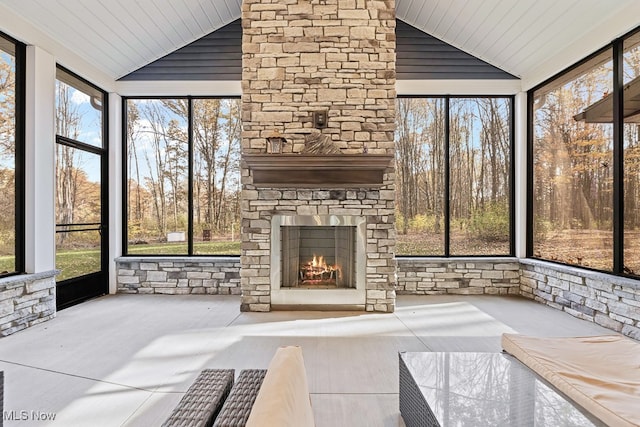 sunroom / solarium with an outdoor stone fireplace, vaulted ceiling, and wood ceiling