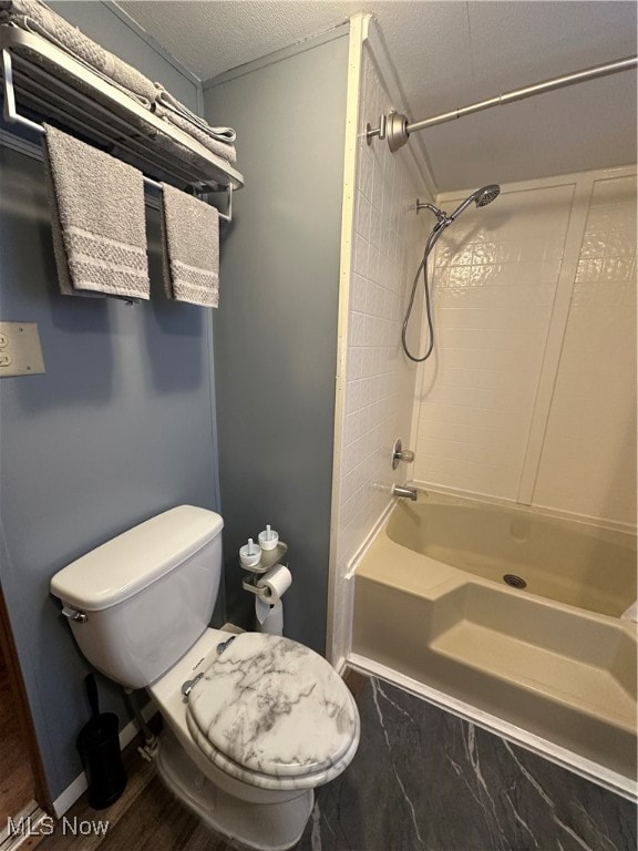 bathroom with a textured ceiling, toilet, and bathing tub / shower combination