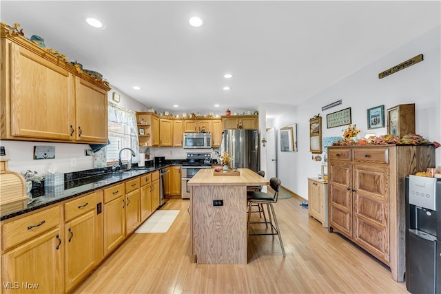 kitchen with stainless steel appliances, sink, light hardwood / wood-style flooring, a center island, and butcher block counters