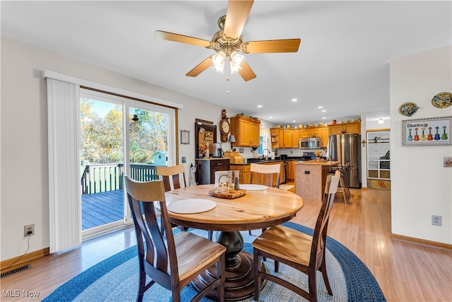 dining room featuring ceiling fan, light wood-type flooring, and sink