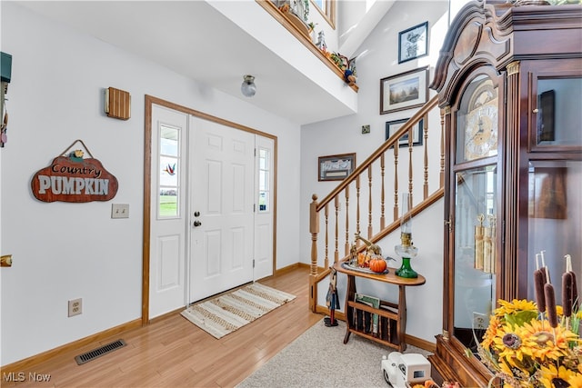 foyer entrance featuring wood-type flooring and vaulted ceiling