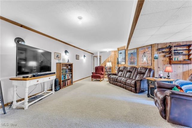 carpeted living room featuring wood walls and crown molding