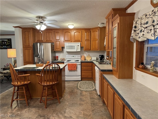 kitchen with a breakfast bar area, sink, crown molding, a textured ceiling, and white appliances