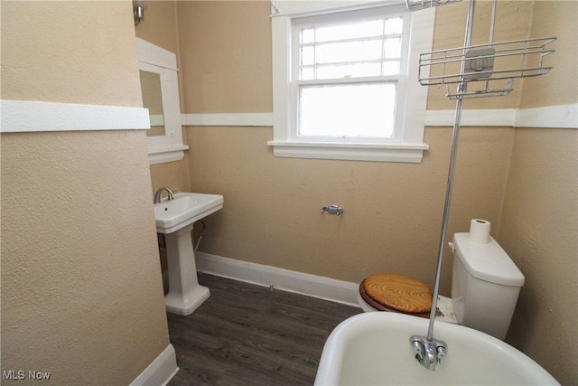 bathroom with toilet, a tub, sink, and wood-type flooring