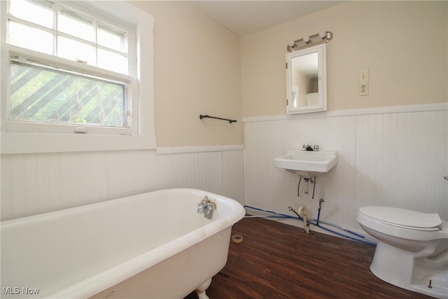 bathroom with hardwood / wood-style floors, toilet, and a washtub