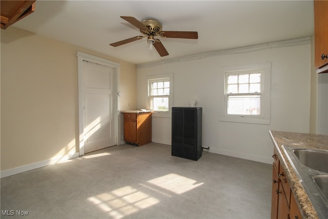 kitchen featuring ceiling fan, light carpet, ornamental molding, and sink