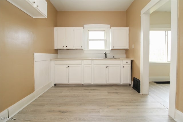 kitchen with sink, light wood-type flooring, and white cabinets