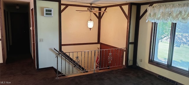 interior space with plenty of natural light and dark colored carpet