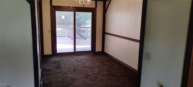 empty room featuring a notable chandelier, dark colored carpet, and a healthy amount of sunlight