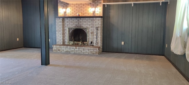 unfurnished living room featuring a brick fireplace, carpet floors, and wood walls