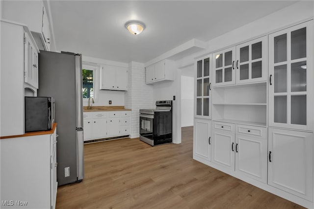 kitchen with light hardwood / wood-style floors, white cabinets, stainless steel range with electric cooktop, and sink