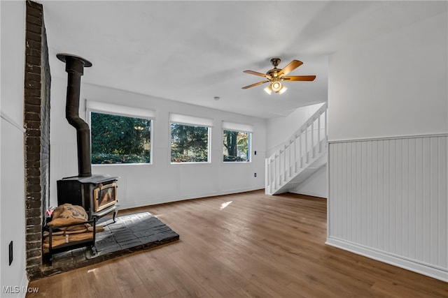 living room featuring ceiling fan, wood-type flooring, and a wood stove