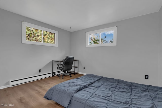 bedroom with a baseboard radiator, hardwood / wood-style floors, and multiple windows