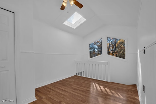 additional living space featuring lofted ceiling with skylight, hardwood / wood-style floors, and ceiling fan