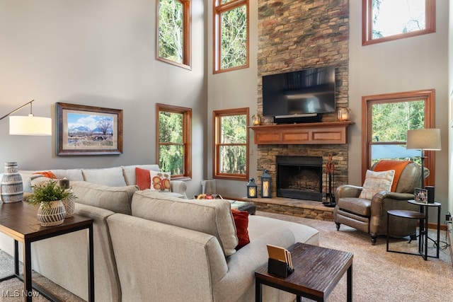 living room with a fireplace, a towering ceiling, plenty of natural light, and carpet flooring