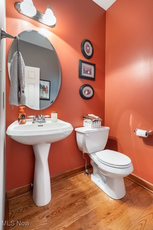 bathroom with hardwood / wood-style floors, toilet, and sink