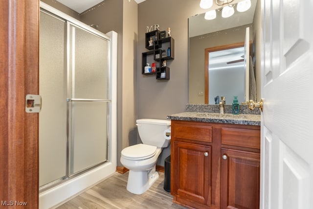 bathroom with hardwood / wood-style floors, vanity, toilet, and a shower with door