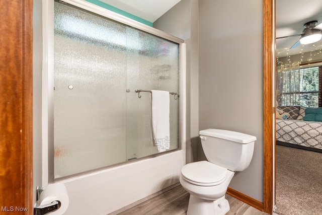 bathroom featuring ceiling fan, hardwood / wood-style floors, enclosed tub / shower combo, and toilet