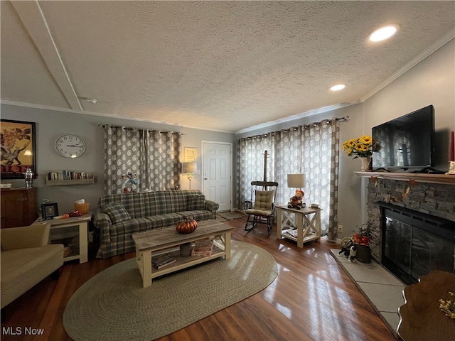 living room with a stone fireplace, ornamental molding, hardwood / wood-style flooring, and a textured ceiling