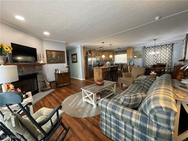 living room with a fireplace, a textured ceiling, dark hardwood / wood-style flooring, crown molding, and a notable chandelier