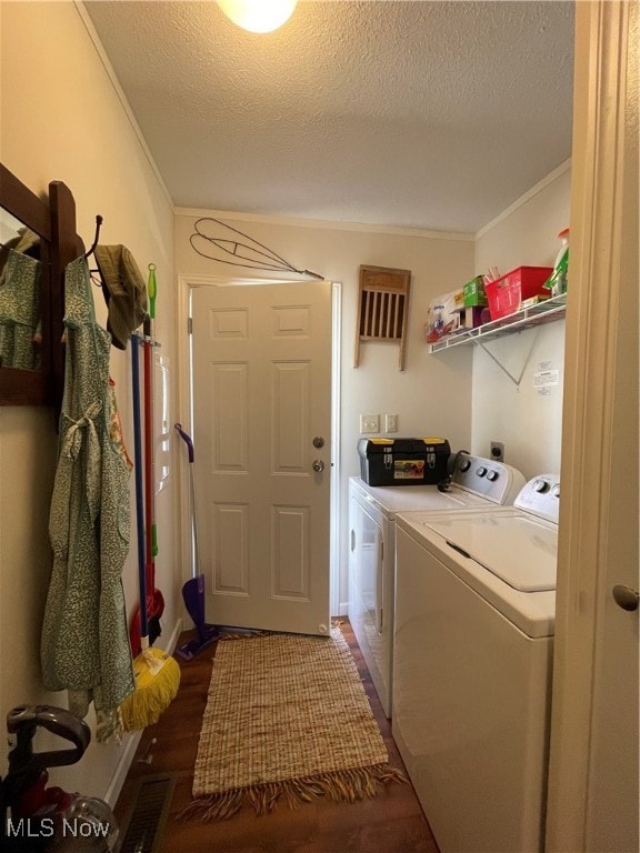 laundry area featuring a textured ceiling, crown molding, independent washer and dryer, and dark hardwood / wood-style floors