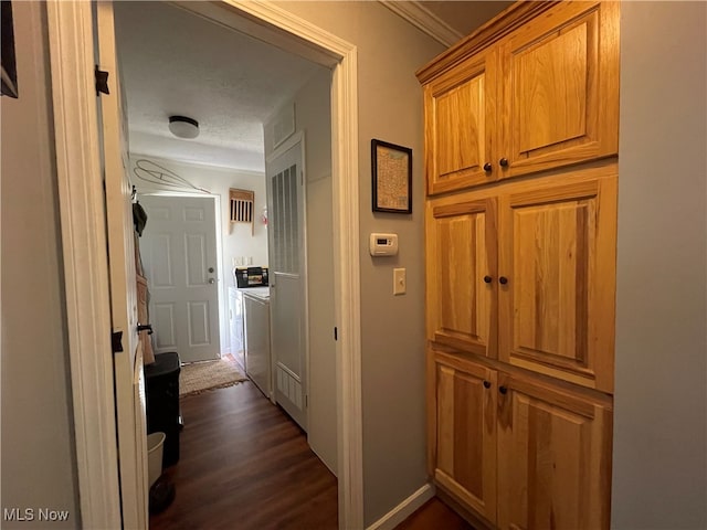 hallway with a textured ceiling, washer / clothes dryer, dark hardwood / wood-style flooring, and ornamental molding