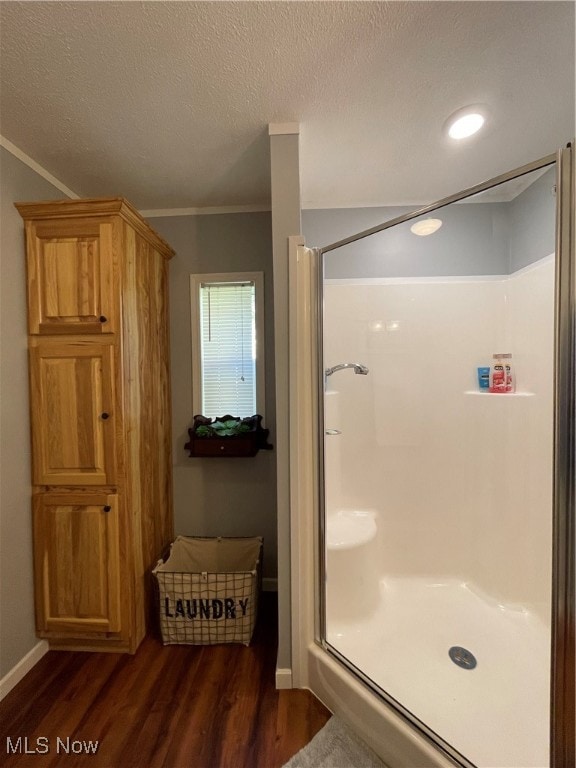 bathroom with ornamental molding, walk in shower, hardwood / wood-style flooring, and a textured ceiling