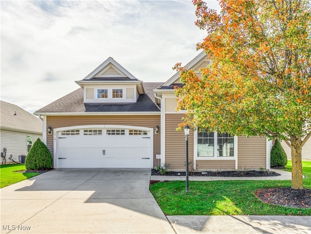 view of front of home featuring central AC, a garage, and a front lawn