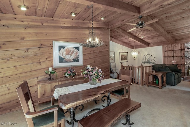 carpeted dining room with vaulted ceiling with beams, wooden walls, wood ceiling, and ceiling fan with notable chandelier