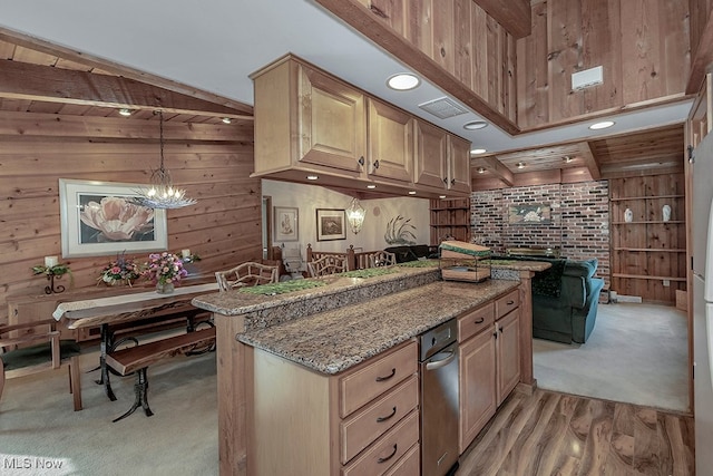 kitchen with wooden walls, light brown cabinets, light stone counters, and pendant lighting