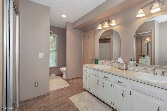 bathroom featuring vanity, toilet, tile patterned floors, and a textured ceiling