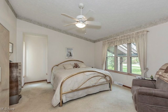 bedroom featuring light carpet, a textured ceiling, and ceiling fan