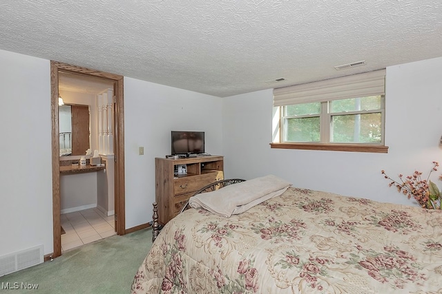 carpeted bedroom with a textured ceiling and ensuite bathroom