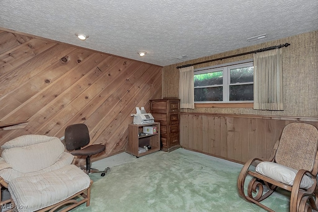 sitting room featuring light carpet, a textured ceiling, and wood walls