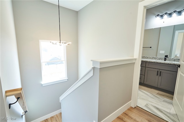 hall with sink, light hardwood / wood-style flooring, and a chandelier