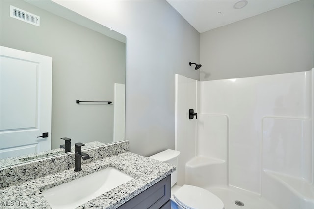 bathroom with vanity, toilet, and a shower